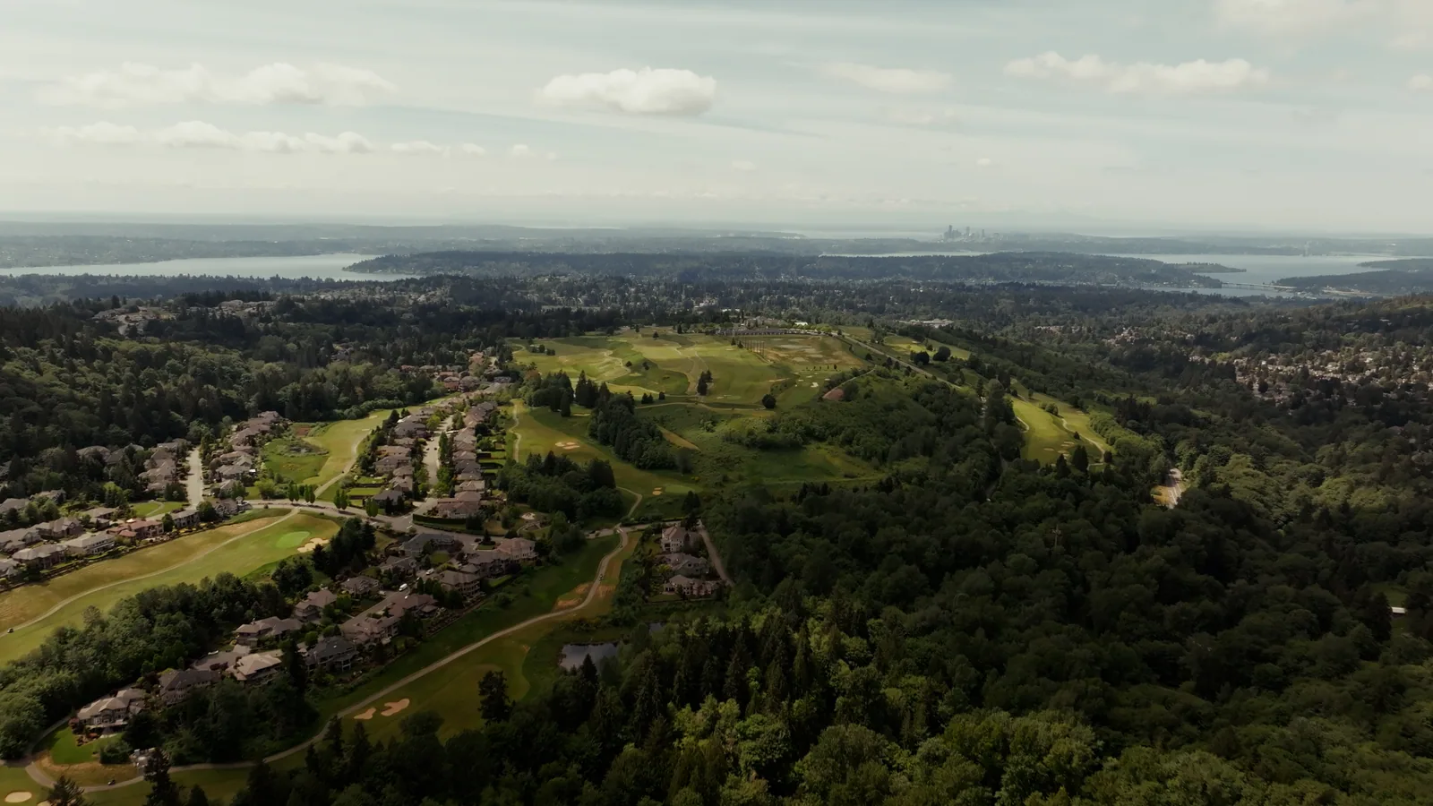 Aerial view of golf fairways surrounded by homes and wooded hills